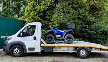 ATV being transported safely on a flatbed tow truck.