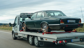 Vehicle secured on tow platform for professional transport service.